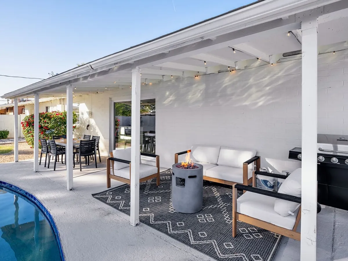 An inviting backyard scene featuring a sparkling swimming pool, a cozy fire pit, and a well-appointed outdoor seating area. Lush landscaping and comfortable seating make this an ideal space for relaxation or informal gatherings after a busy day.