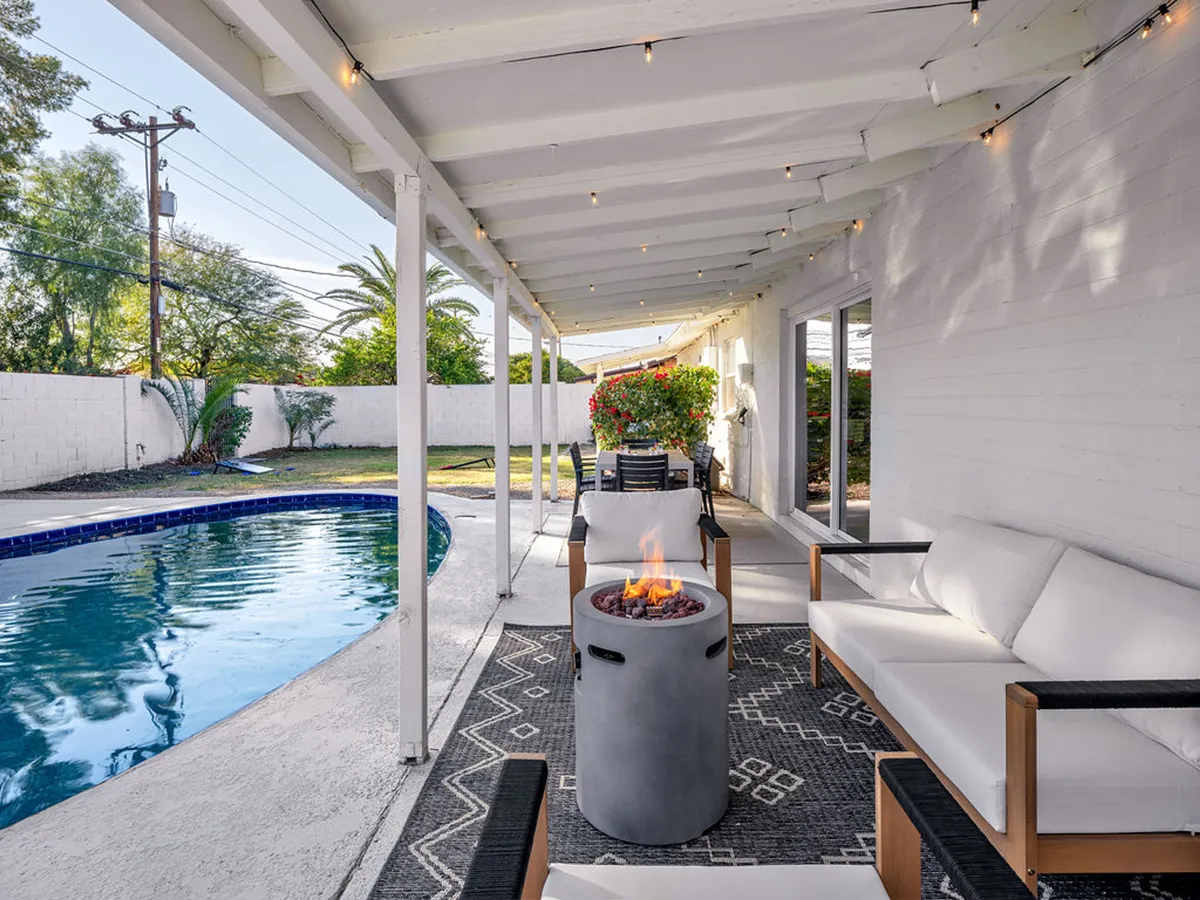 A serene outdoor living space featuring a swimming pool, cozy fire pit with surrounding seating, and attractive landscaping. The scene is set for evening relaxation and social gatherings, with a tranquil atmosphere as the sun sets.